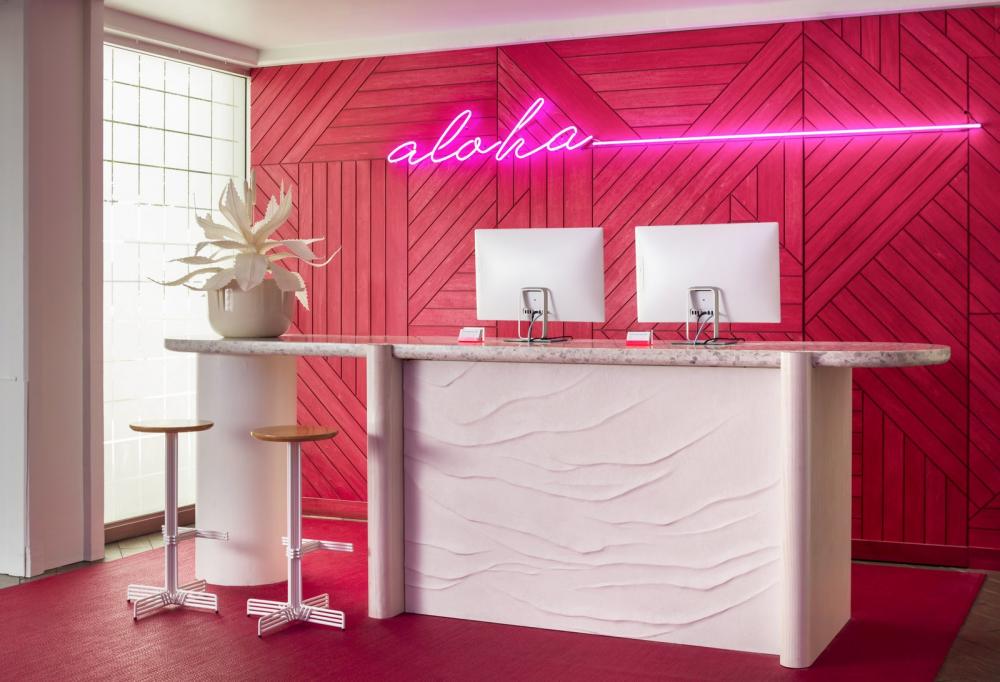 Bức tường tại quầy lễ tân có màu hồng neon như làm nổi bật hơn logo “Aloha” của khách sạn