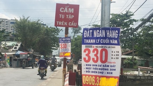 Biển rao bán đất nền thanh lý giá rẻ treo trên cột đèn, đường giao thông, xe máy