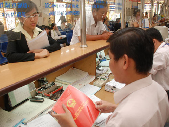 trong 1 ngân hàng, nhiều khách hàng đang ngồi chờ, 1 người đàn ông và 1 người phụ nữ đang trao đổi với nhau