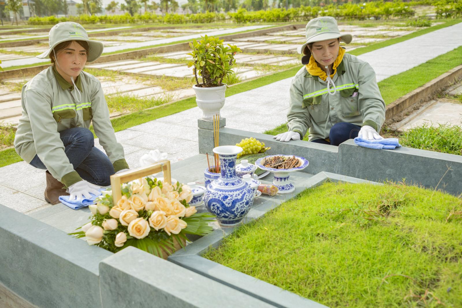 Hai người phụ nữ đang ngồi lau dọn phần mộ