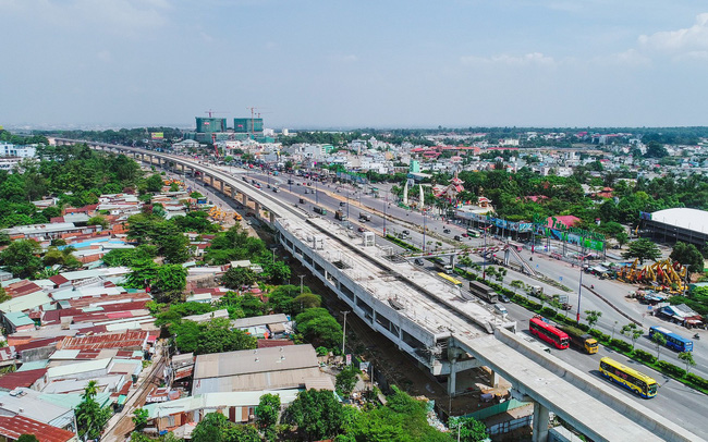 tuyến đường sắt trên cao, xung quanh có nhiều nhà ở, cây cối, xe cộ