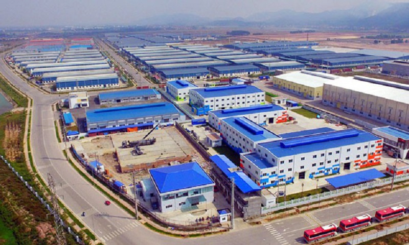 Ảnh toàn cảnh một khu công nghiệp nhìn từ trên cao với nhiều nhà xưởng màu xanh mái trắng nằm cạnh các con đường lớn.