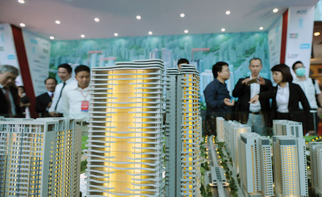 Ảnh chụp sa bàn một dự án bất động sản gồm nhiều tòa nhà cao tầng, xung quanh có nhiều người đứng xem.