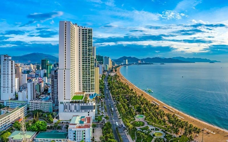 Bất động sản nghỉ dưỡng ven biển phía Nam, nhà cao tầng, bãi cát, nền trời xanh.